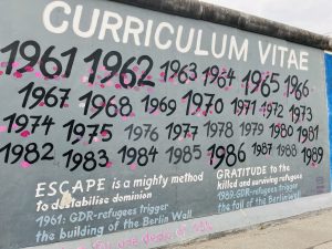 Schrift Künstlerinformationen wie "SUSANNE KUNJAPPU JELLINEK" zu sehen. Im oberen Bildbereich ist ein bewölkter Himmel zu erkennen.